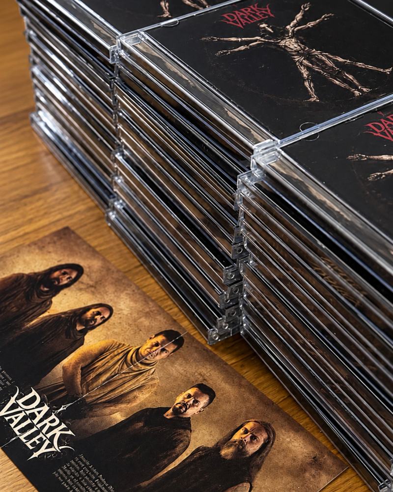 Pila de discos de Mártir en cajas transparentes junto a una postal con la foto de la banda